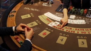 Brown casino table with dealer and player hands